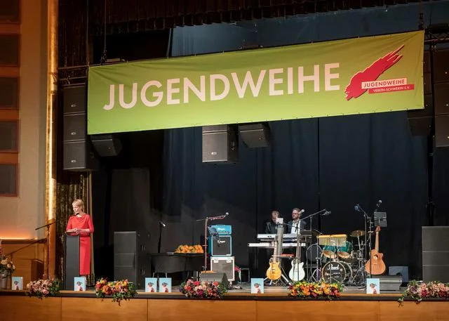 Festlich geschmückte Bühne mit großem Jugendweihe-Banner