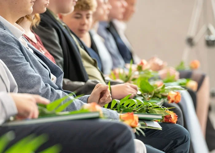 Sitzende Jugendliche mit Rosen während ihrer Jugendweihe